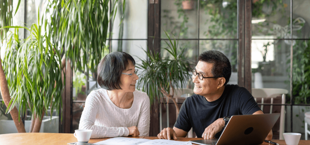 Two people sitting at a table and smiling as they look at each other